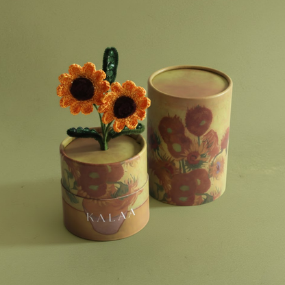 Decorative cylindrical container with floral design and small crocheted flowers on a green background