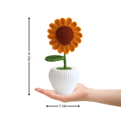 Crocheted sunflower in a white pot held in a hand with measurements indicated.